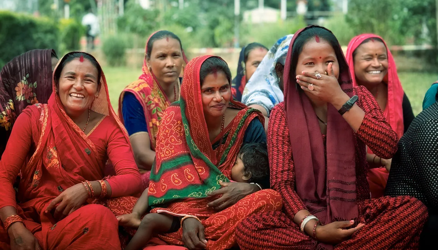 A group of Nepali women sit together, all wearing red clothing.