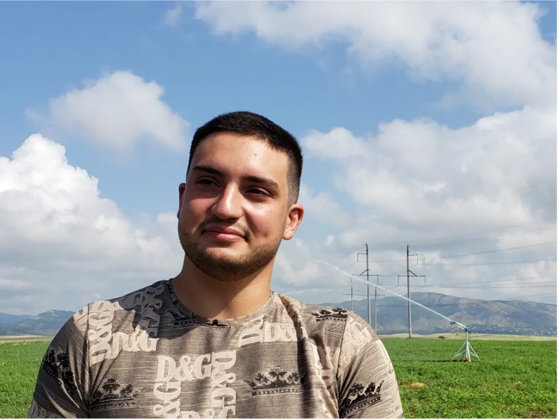 Portrait of a man outdoors, agricultural field behind him.