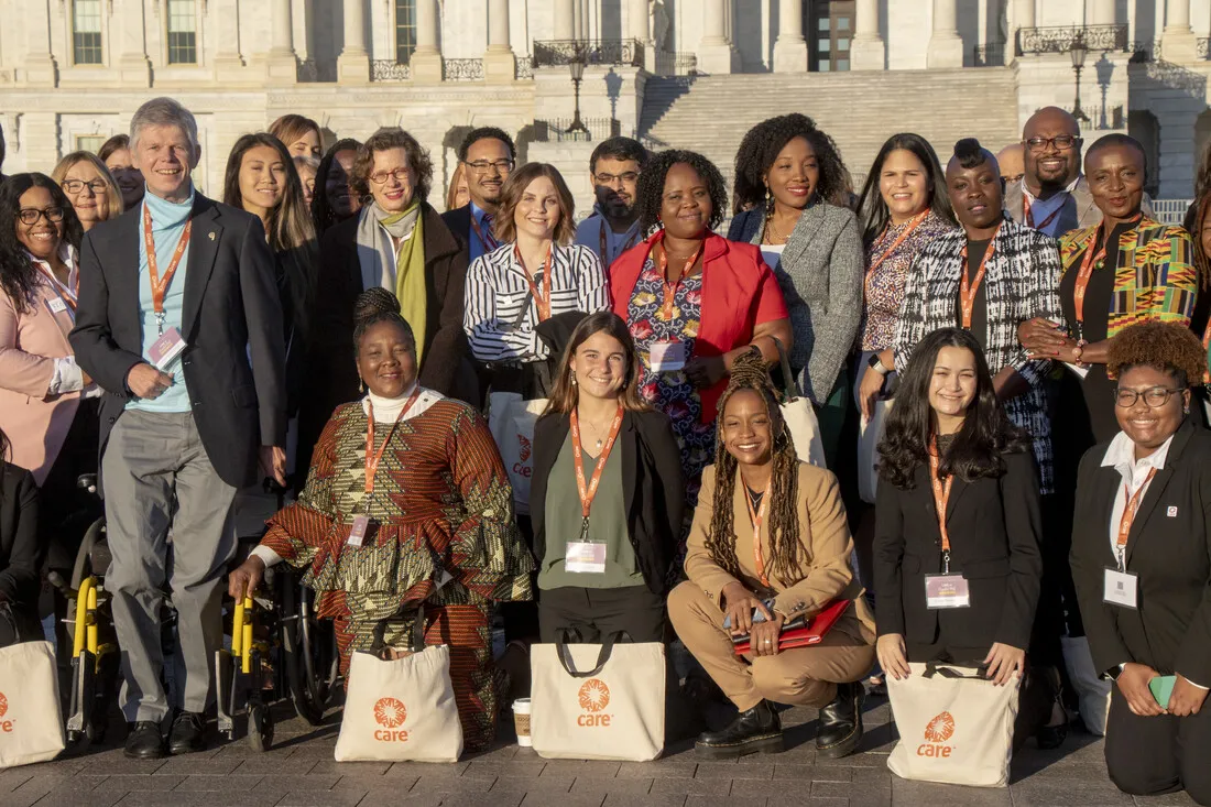 A group of men and women posing for a picture with Care bags in front of Capitol Hill.
