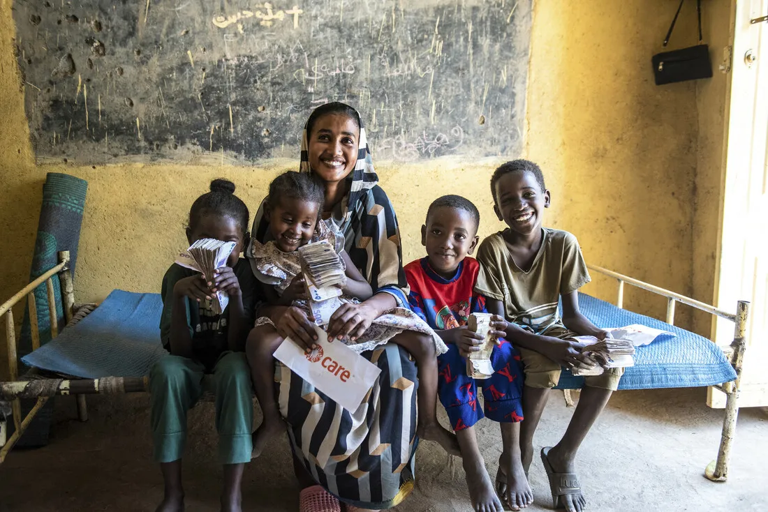 A woman sitting with four children holding cash.