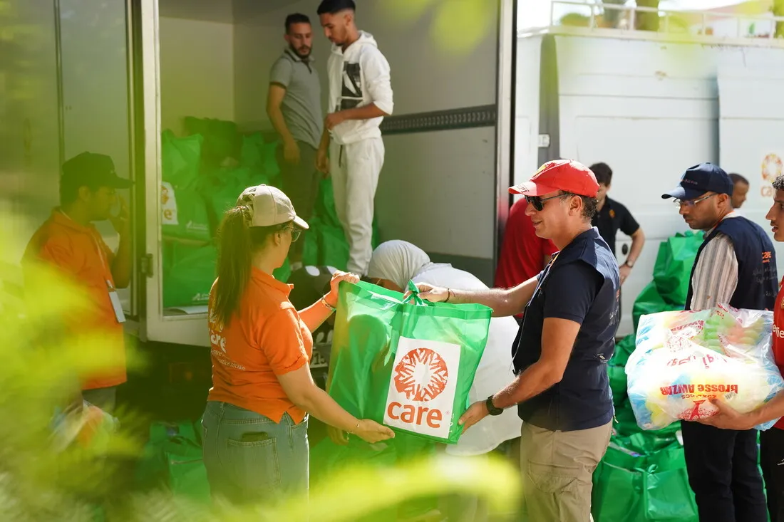 CARE staff carrying food supplies.