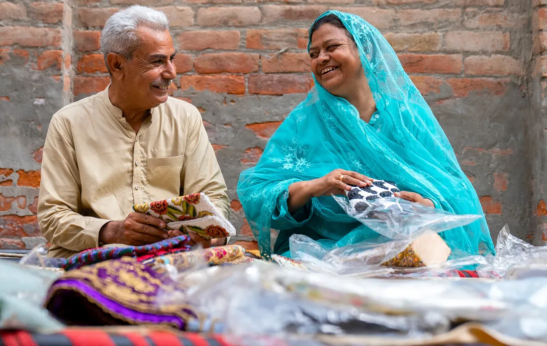 A man and woman are packing an item and smiling at one another.