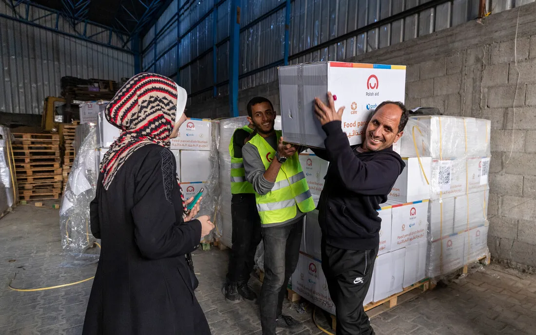 A group of people collaborating distributing food boxes with the Care logo on the boxes.