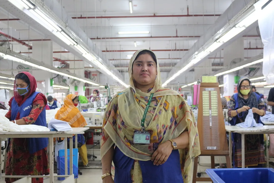 A Bangladeshi woman stands amid workers at a garment factory.