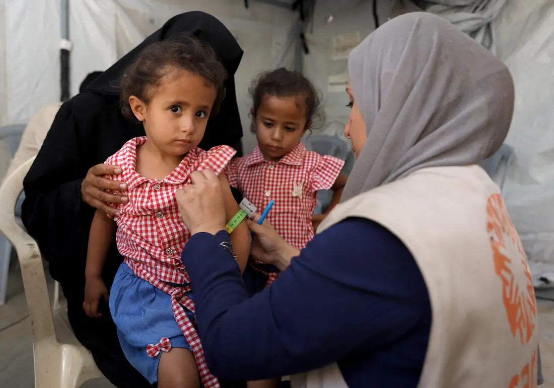 A CARE staff member measures a young girl's arm.