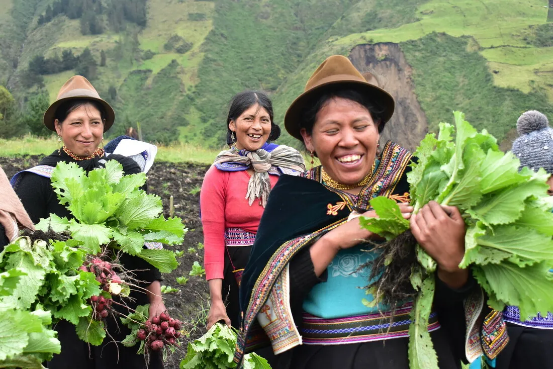 A group of women smiling and holding vegetables.
