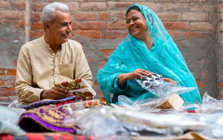 A man and woman smile at each other while looking through textiles.